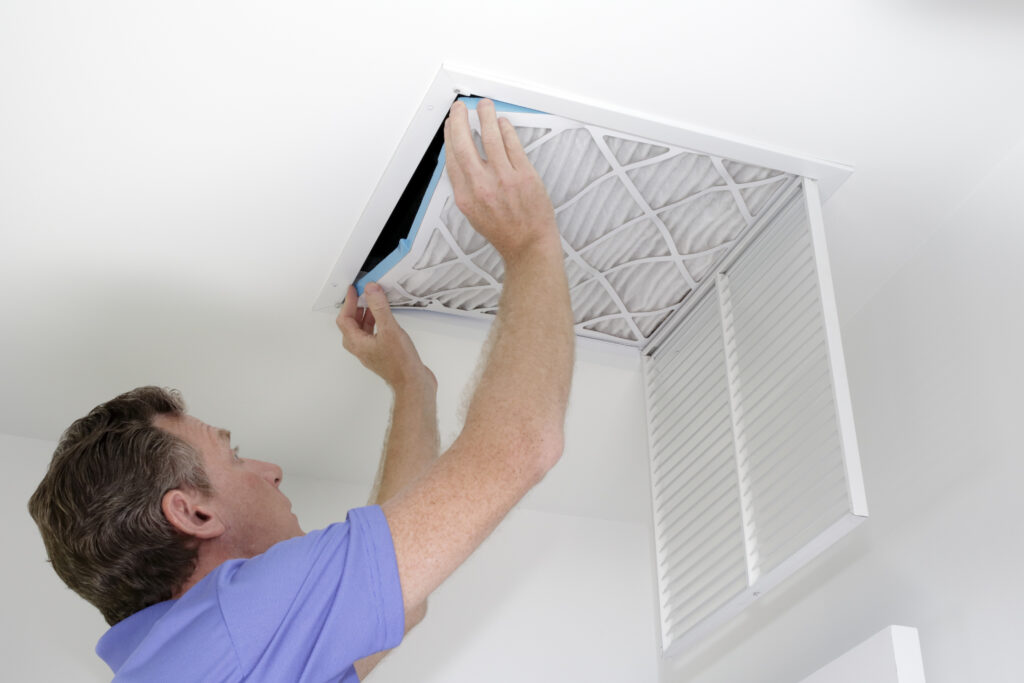 Homeowner replacing an air filter overhead